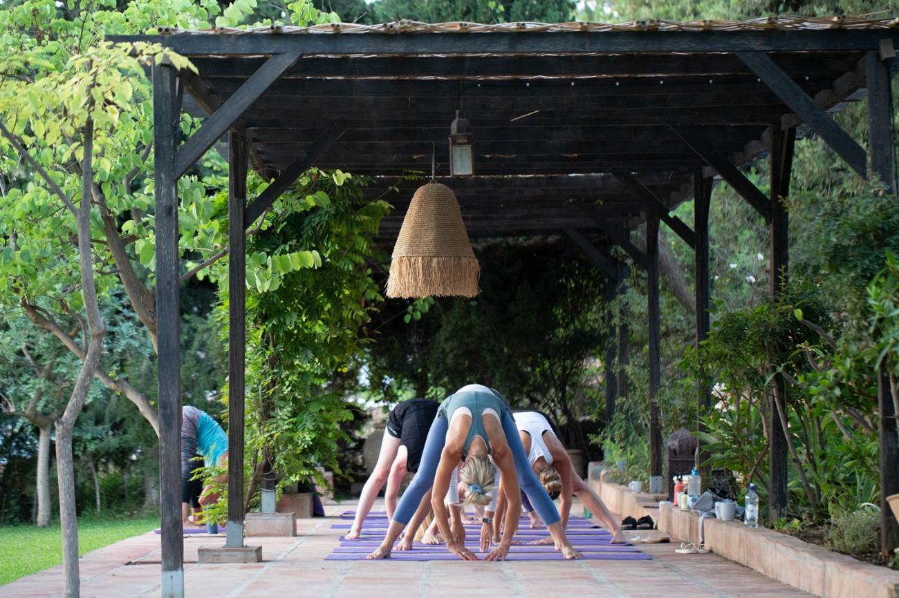 En gruppe deltakere gjør yoga sammen i det frodige uteområdet på Finca Parrilla.